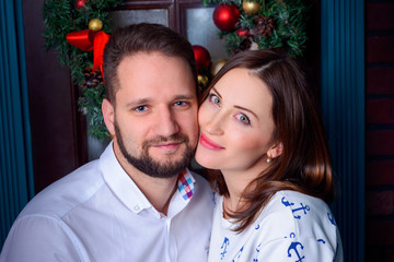 Young couple embrace on a background of the door with  Christmas wreath - 110657482