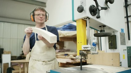  Professional carpenter in his workshop, cutting timber with a band saw