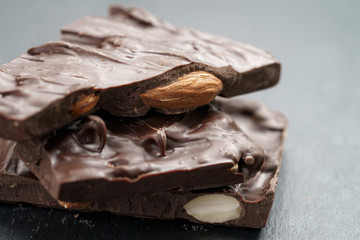 homemade chocolate with almond nuts in stack on slate board, shallow focus