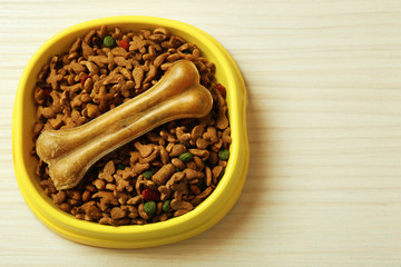 Dog food in plastic bowl on wooden background