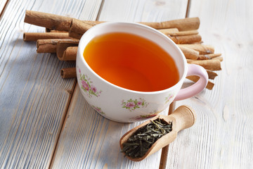 Cup of tea, dried tea leaves and cinnamon sticks
