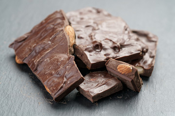 reverse side homemade chocolate with almond nuts on slate board, shallow focus