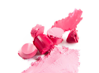 Crushed sliced pink lipstick isolated on white background. Texture of damaged pink colored lipstick on white. Pieces of colorful lipstick closeup.   