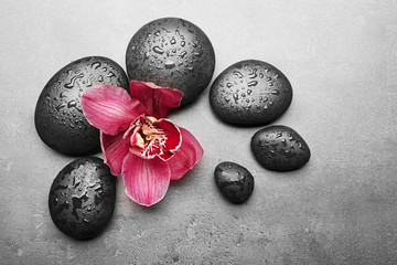 Spa stones and red orchid on grey background