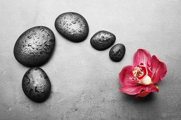 Spa stones and red orchid on grey background