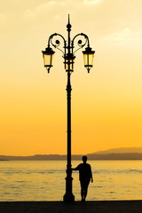 Woman silhouette watching sun in a sunset and lean on lantern
