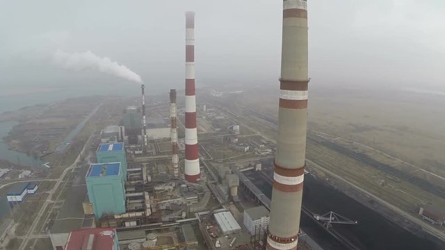 Aerial shot of power plant industrial facilities and huge pipes smoking polluting the air