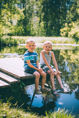 Two little boys friends sits outdoors in nature