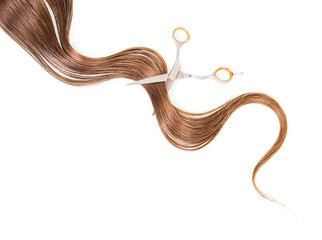 Lokon long brown hair and barber scissors isolated on white.