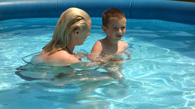 Mother learning her son to swim in the pool 