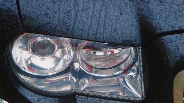 Car headlight in the rain, raindrops running down the glass