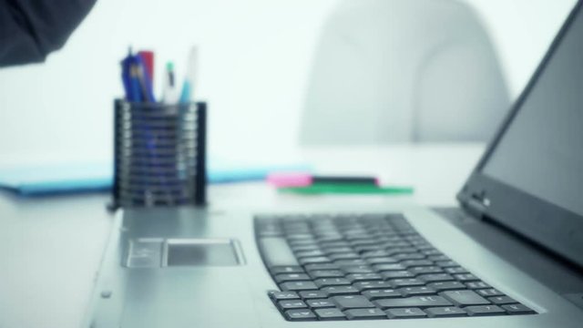 Stressed businessman smashing breaking computer keyboard with fist slow motion