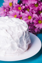 White creamy cake with flowers on the blue wooden background