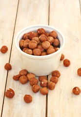 Hazelnuts in the bowl on the wooden background