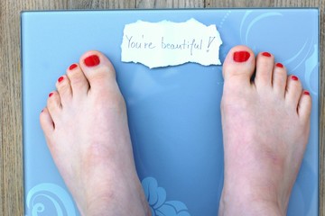 Feet on scales with message on the wooden background