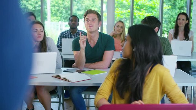  Group of students in class, listening to the teacher and asking questions