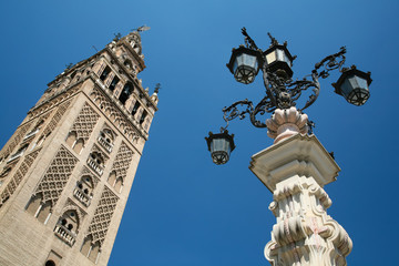 Fototapeta na wymiar famous belfry named Giralda in landmark catholic cathedral Saint Mary of the See, public gothic monument year 1507, World Heritage UNESCO, and old vintage streetlight in Seville, Andalusia, Spain