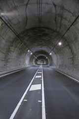 landscape straight grey lonely road tunnel with two lanes, white painting dividing lines in asphalt and light, in Spain Europe