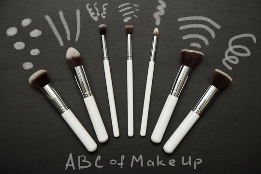 Make up brushes on black background with chulk pictures.