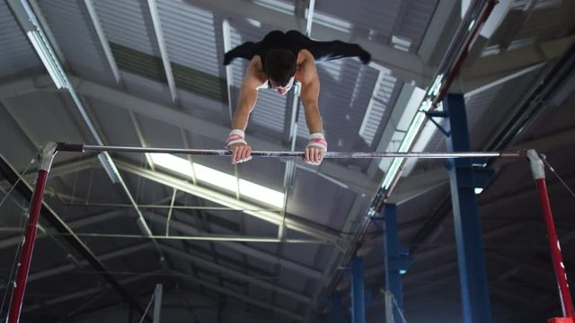  Professional male gymnast training on horizontal bar at the gym