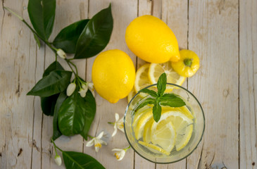 Лимонад украшенный веткой цветущего лимонного дерева на деревянном фоне