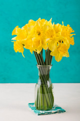 Yellow narcissus flowers in glass vase Copy space