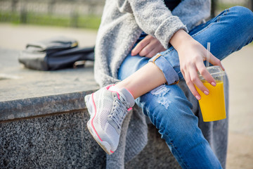 Young beautiful woman, sitting on the street , drinking smoothie.