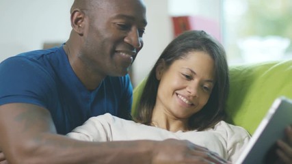  Affectionate pregnant couple relaxing at home with tablet computer - Powered by Adobe