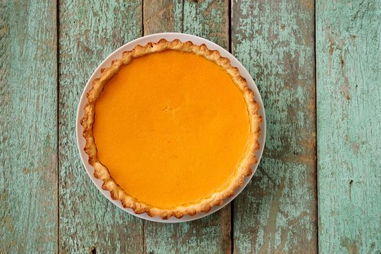 Homemade oldfashioned open round pumpkin pie on old painted wood