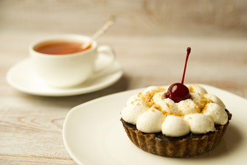 Cake with cherry and a cup on the table