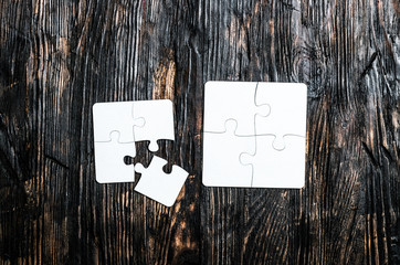 two little white puzzles on dark wooden table top view