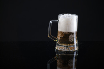 Beer glass with background and shinny reflection on bottom with beer falling into glass