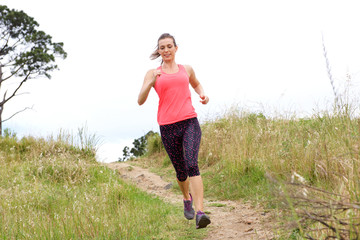 Full length portrait of sporty woman running on dirt path