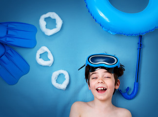 Child lying on blue blanket with swimming mask and flippers