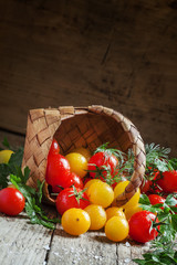 Colorful cherry tomatoes in a wicker basket, vintage wooden back