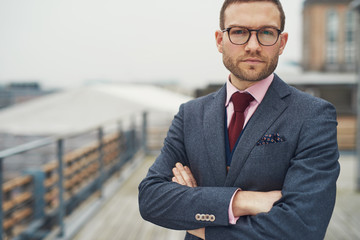 Stylish businessman standing outside near railing
