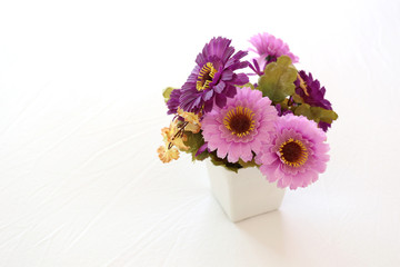 Vintage pink and violet artificial flowers on a white fabric in