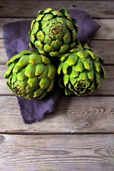 fresh artichokes on rustic wooden background  with lemon, weighe