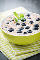 Buckwheat porridge in a bowl with mint leaves and blueberries.