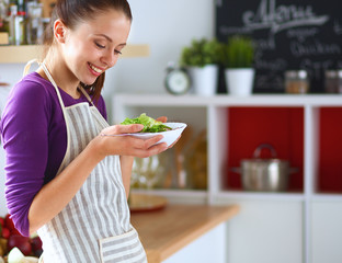 Young woman eating fresh salad in modern kitchen