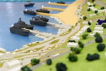 Warships wharf scale model, layout of army naval base, miniature of military harbor with small models of ships, piers, docks, buildings and port driveways, selective focus 