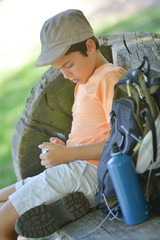 Young boy seeking his path on a phone during a hike