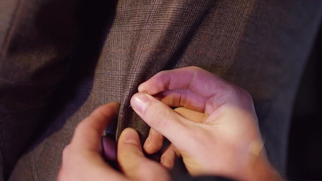  Close up on the hands of a tailor fitting a suit for a customer. Shot on RED Epic.