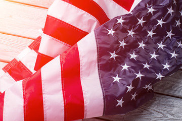 Naklejka premium Creased American flag in sunlight. Crumpled banner on wooden background. Every day gives new chances. Never give up.