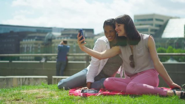  Happy attractive female friends posing for selfie outdoors in the city