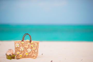 Closeup beautiful bag with frangipani flowers and coconut on white beach