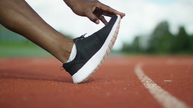  Close up on hands & feet of unrecognisable athlete at the running track 