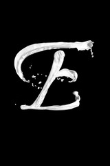 Letter E made of milk, isolated on black
