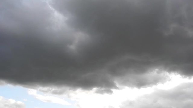 Zeitrafferaufnahme von hellen und sehr dunklen Wolken, die &uuml;ber den blauen Himmel ziehen 