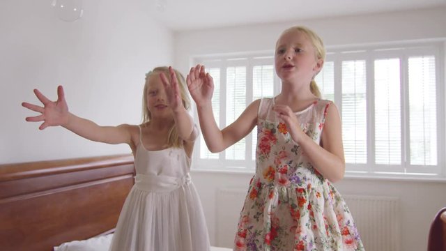  2 Little girls having fun at home, playing in the bedroom with bubbles